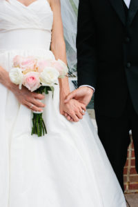 newly weds holding hands, close up with bouquet
