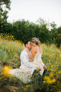 Bride in groom in yellow wildflowers following mountain side elopement