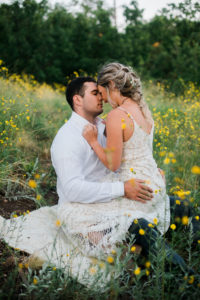Bride in groom in yellow wildflowers following mountain side elopement