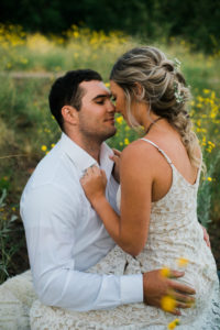 up close photo of bride in groom in yellow wildflowers following mountain side elopement